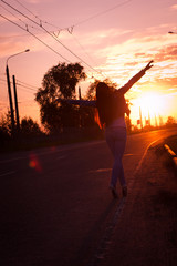 Young woman standing on road and looking to a sunset sunrise