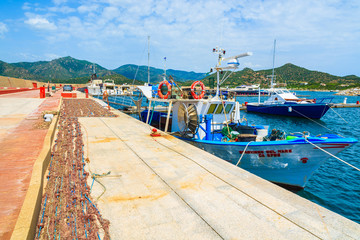 Fishing boat and net on shore in Porto Giunco, Sardinia island