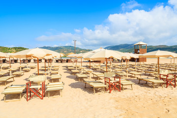 Sunbeds with umbrellas on Sa Colonia beach, Sardinia island