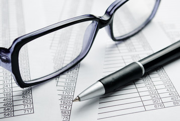 Fototapeta premium Eyeglasses and Pen on Top of Report Papers