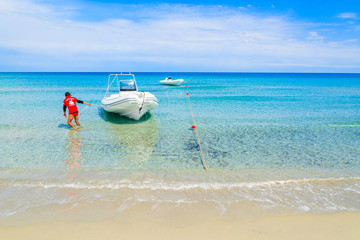 Fototapeta na wymiar Lifeguard pulling boat to shore on Villasimius beach, Sardinia