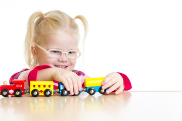 Child in eyeglasses playing toy train isolated