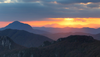 Fototapeta na wymiar Dramatic sunset rays behind silhouette of of mountain