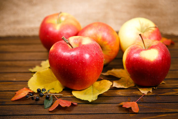 apples and fallen leaves on old wooden table