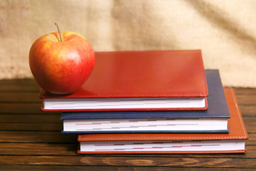  Notebooks and apple on wooden table