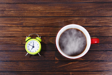 Obraz na płótnie Canvas Tea or coffee cup and alarm clock on wooden table.
