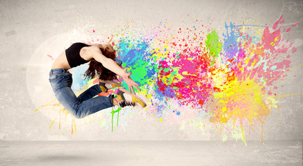 Happy teenager jumping with colorful ink splatter on urban backg
