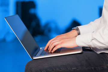 Businessman pressing modern laptop computer on colorful backgrou