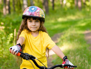 Naklejka premium little girl on bike looking at camera and smiling