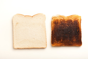 Two slices of bread, raw and burnt toast
