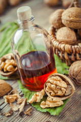 Fototapeta na wymiar Walnuts, bottle of tincture or oil and wicker basket with nuts o