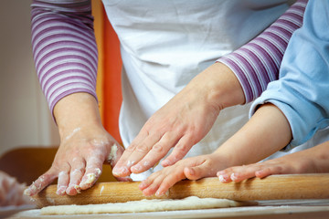 Little girl making pizza for lunch with her mother