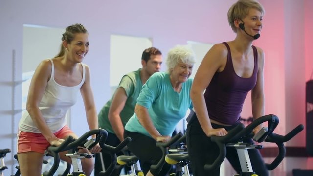 Senioren und Junge Spinning auf Fitness Fahrrad