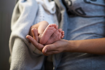 Mom keeps  miniature newborn feet in hands