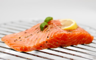 Marinated salmon fillet with lemon on grill, soft focus