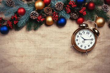 Alarm clock near Pine branches on a table.