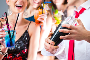 Freunde feiern mit Barkeeper in Cocktailbar