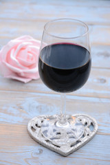 glas rode wijn op houten tafel met hart decoratie en roze roosje - obrazy, fototapety, plakaty