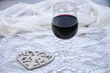 Fototapeten glas rode wijn met hart decoratie en transparante stof © trinetuzun