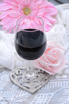 glas rode wijn met roze bloemen en transparante stof