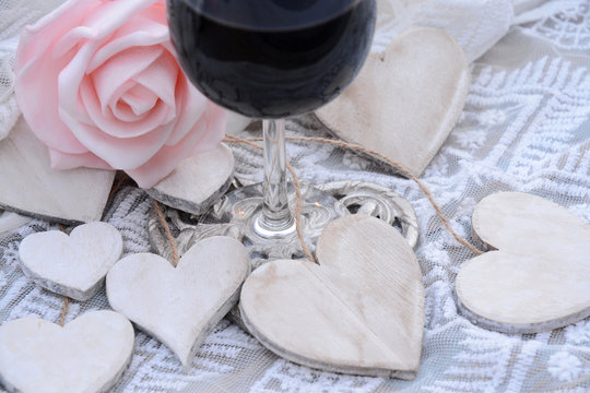 houten hart decoratie met roze roos en deel van glas wijn