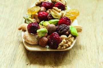 Varieties of dried fruits and nuts on wooden spoon.
