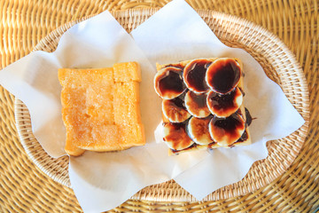 Baked bread buttered and bread chocolate on bamboo plate.