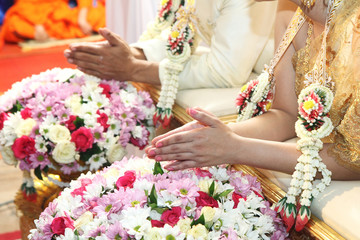Hands pouring blessing water into bride's hands inThai ceremony.