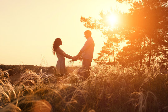 Young couple holding hands. In nature sunrise