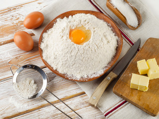 Eggs, flour, sugar, butter on  white  wooden background