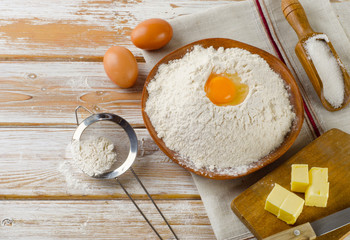 Eggs, flour, sugar, butter on a white  wooden background