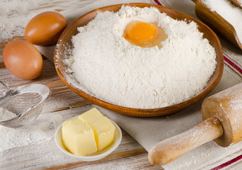 Eggs, flour, sugar and butter on a white  wooden background