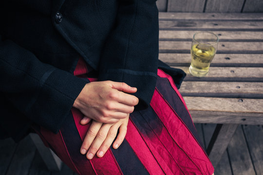 Woman sitting on bench with glass of beer