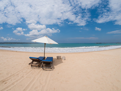 Relaxing couch chairs with parasol on white sandy Beach