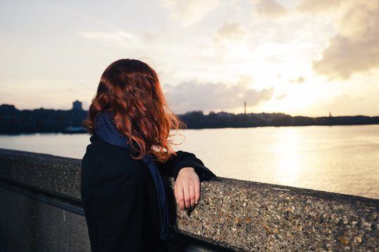 Woman admiring sunset over river in city
