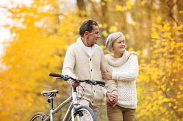 Senior couple with bicycle in autumn park