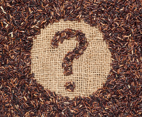 Red rice forming a question mark on burlap fabric