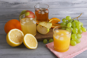 glasses of juice with fresh fruits on grey wooden table