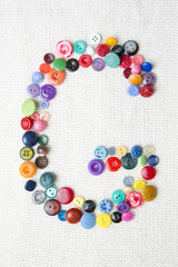 Letter G of the alphabet of buttons of various shapes and colors