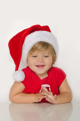 girl in costume of Santa at table and smiling