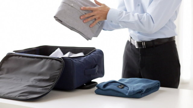 businessman packing clothes into travel bag