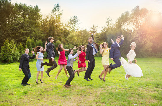 Newlyweds with guest jumping in park