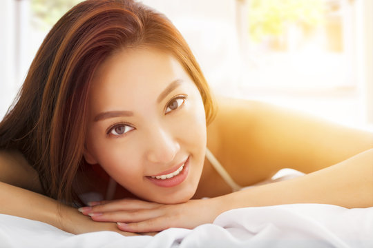 young Beautiful asian woman relaxing on the bed with sunlight ba
