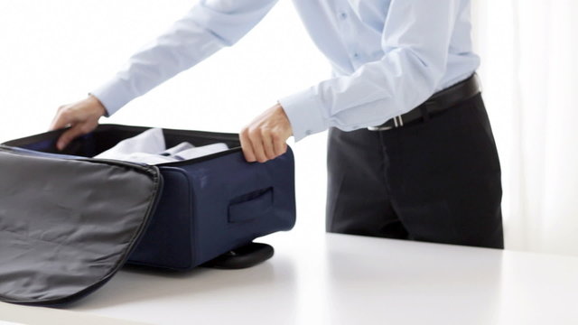 businessman packing clothes into travel bag