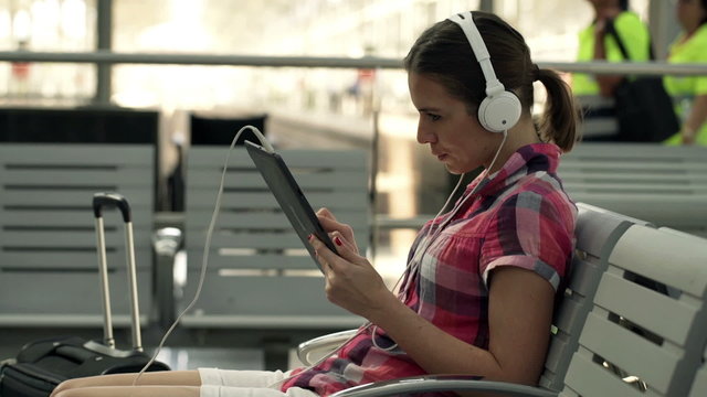 Young woman listening music and looking at something on tablet c