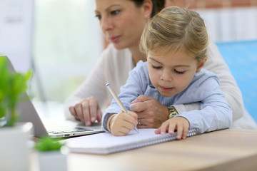 Woman working from home while daughter is drawing