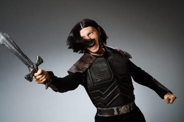 Angry knight with sword against dark background