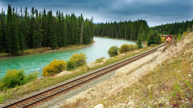 A short train traveling along a mountain Bow river
