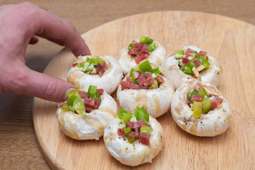 Preparing mushrooms stuffed with ham and pepper