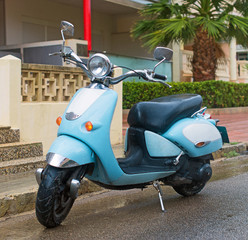 Fototapeta na wymiar Blue scooter parked on the street.